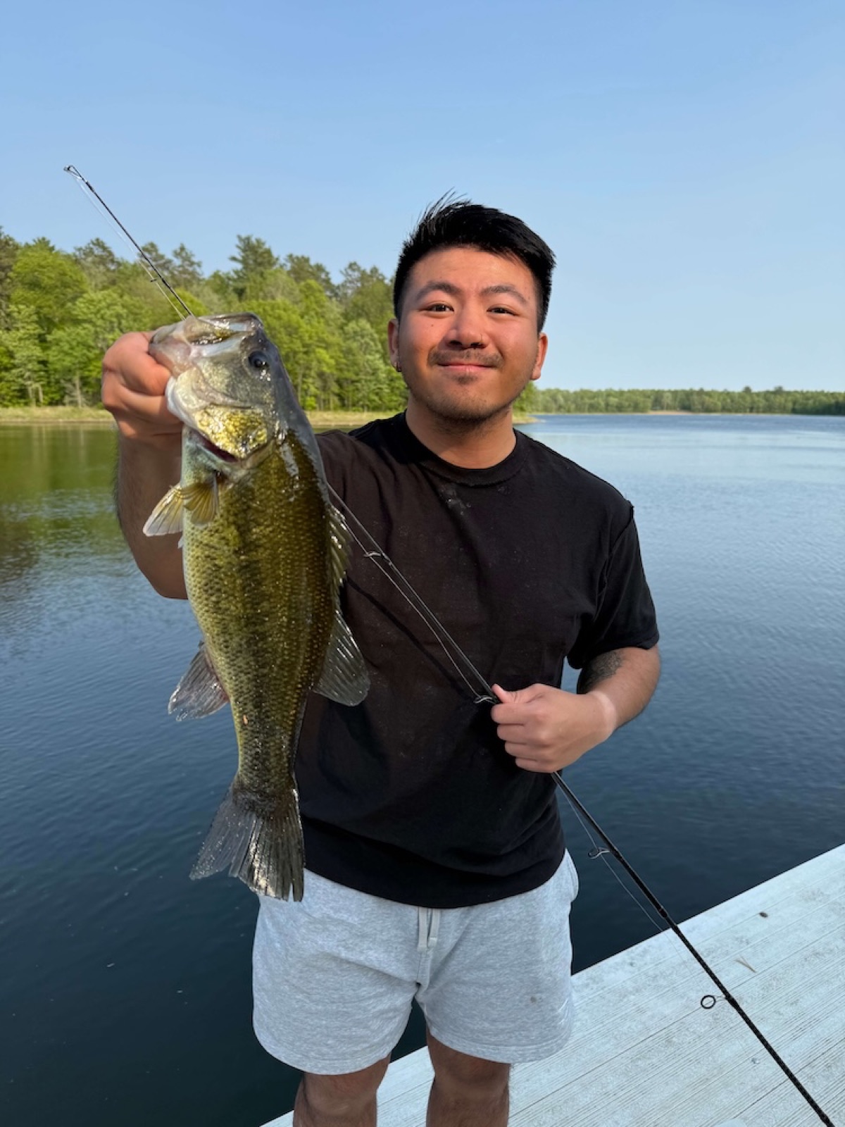 Rocky Yang holding a bass he caught fishing